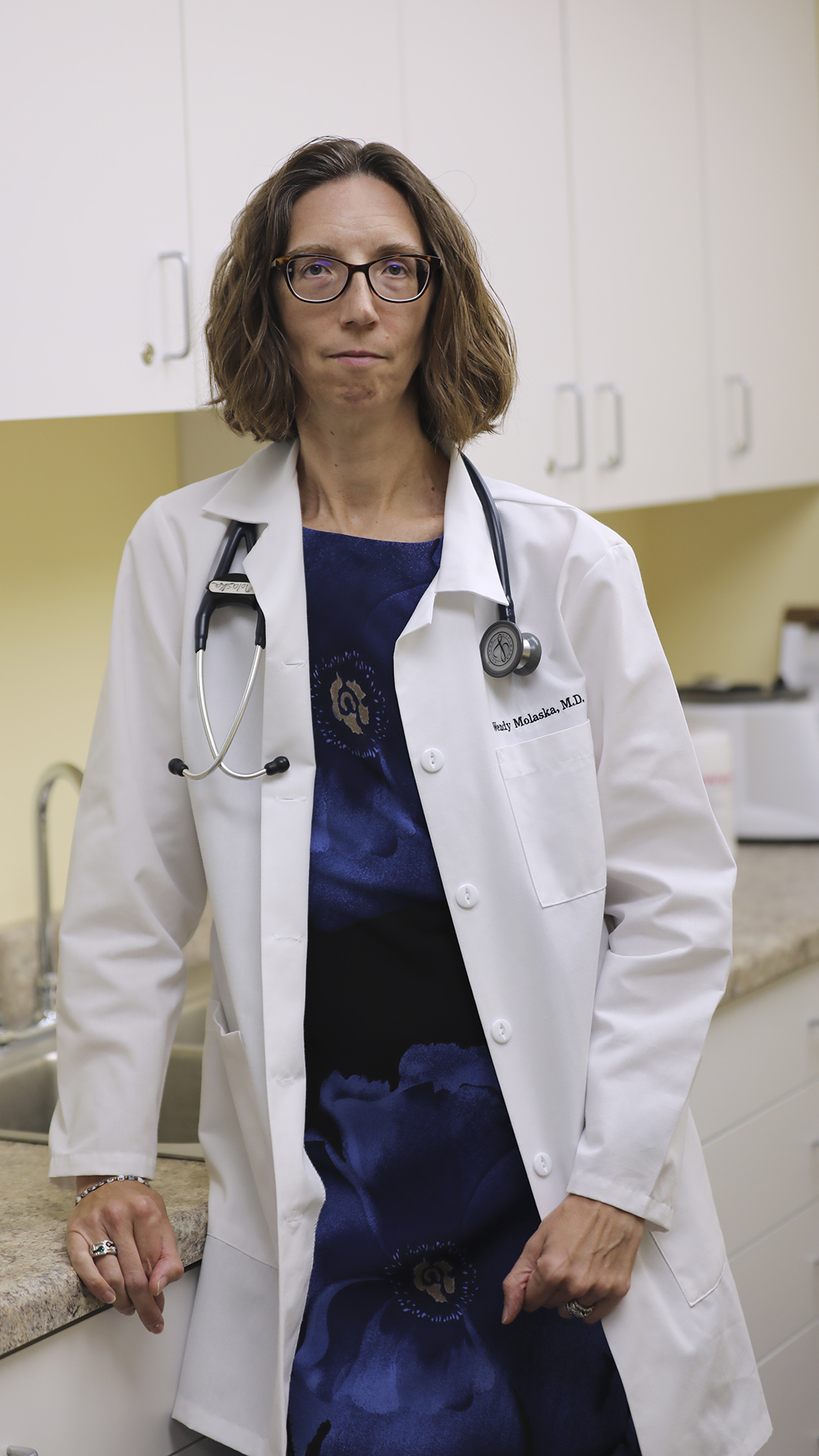 Wendy Molaska stands next to a counter in a medical office, with white cabinets and a sink in the background.