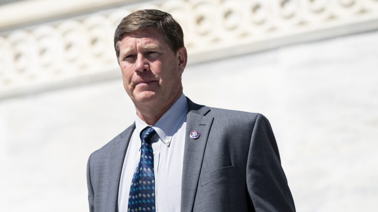 Ron Kind stands in front of a marble wall with a filigree relief pattern.