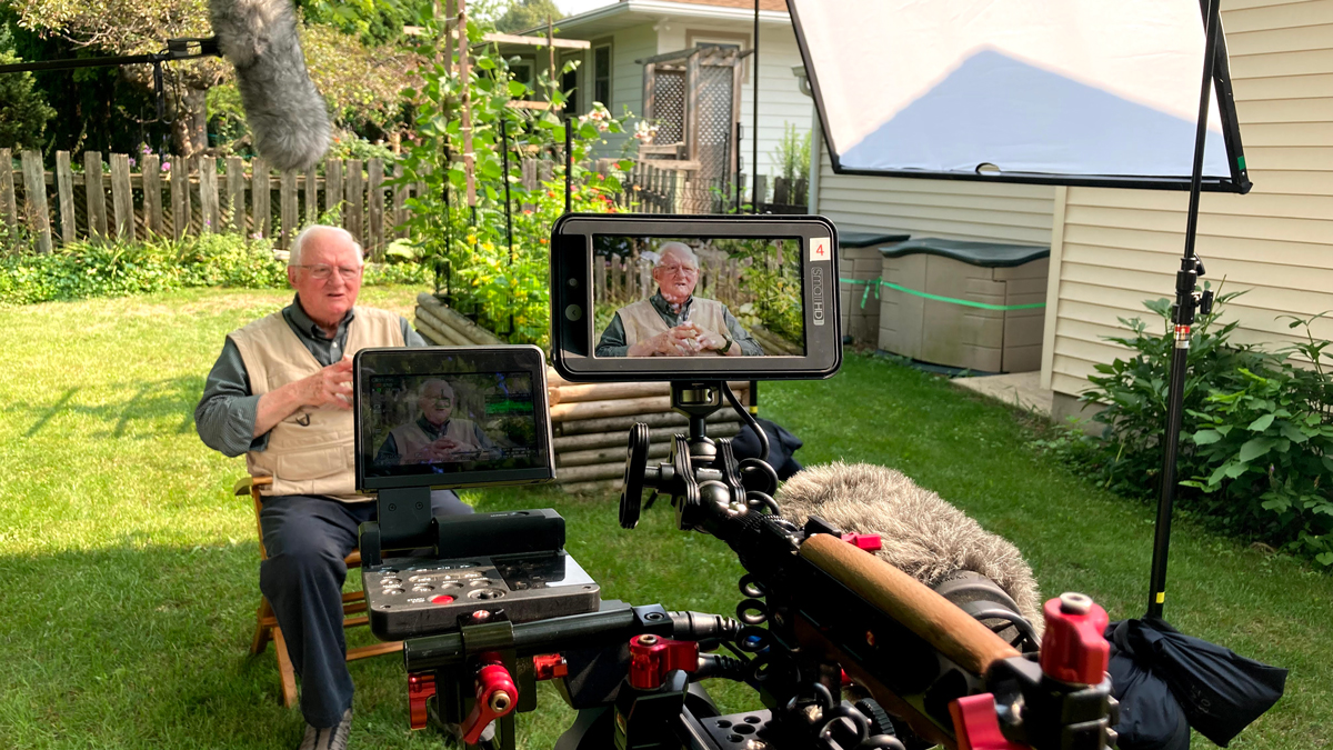 Jerry Apps under a microphone and on camera for an interview in his backyard