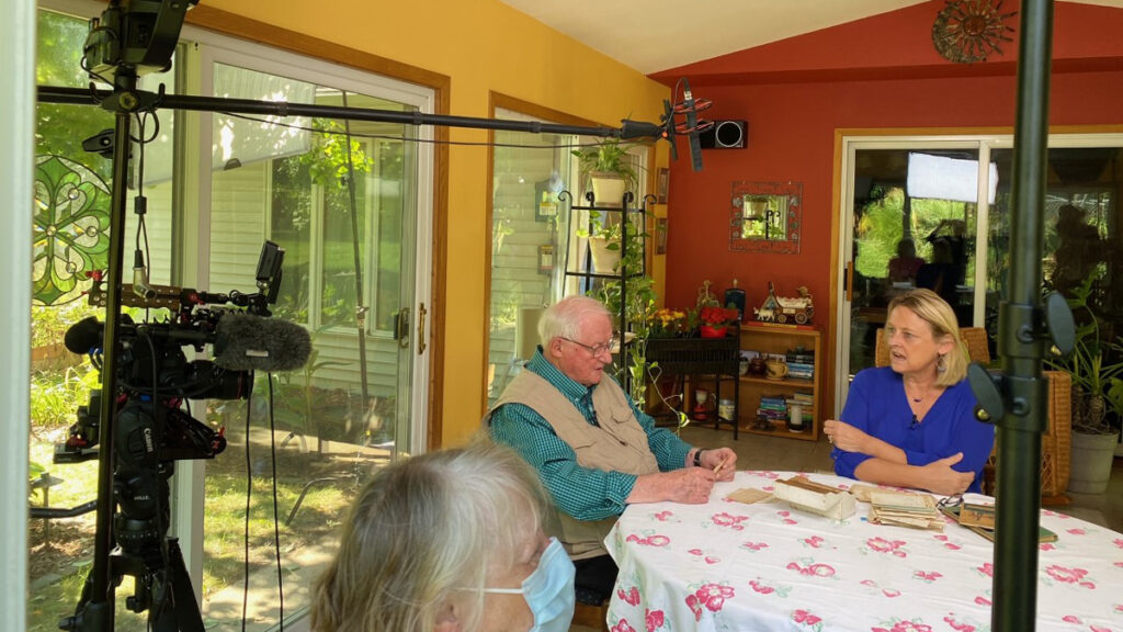 Jerry Apps and Susie Apps-Bodilly sit in her sun porch with lighting and camera equipment set up for an interview.