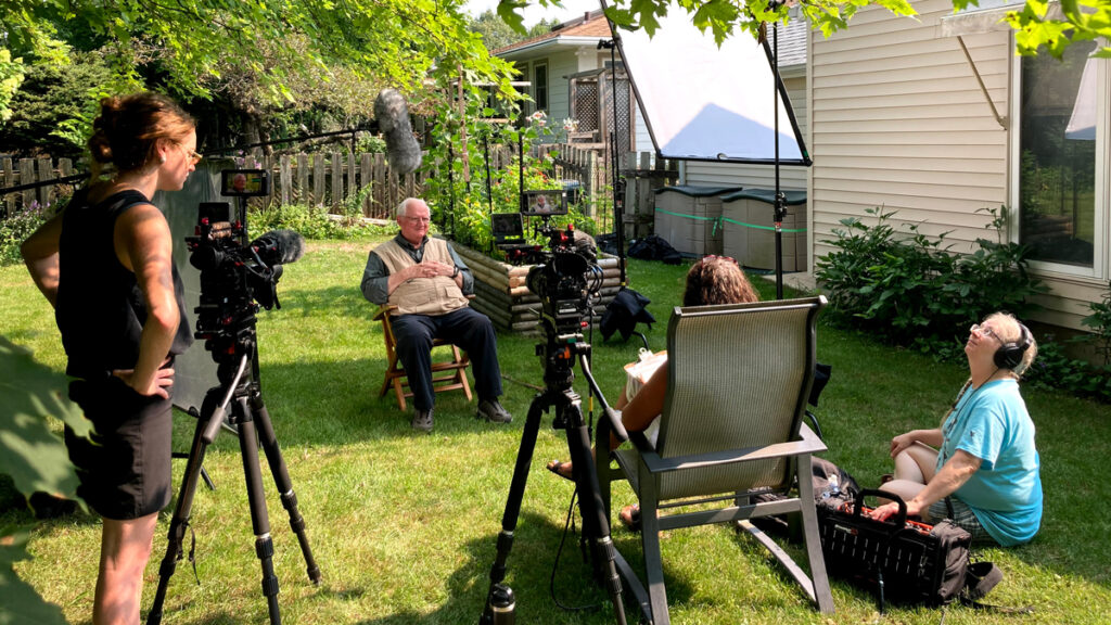 A production crew recording an interview of Jerry Apps in his backyard