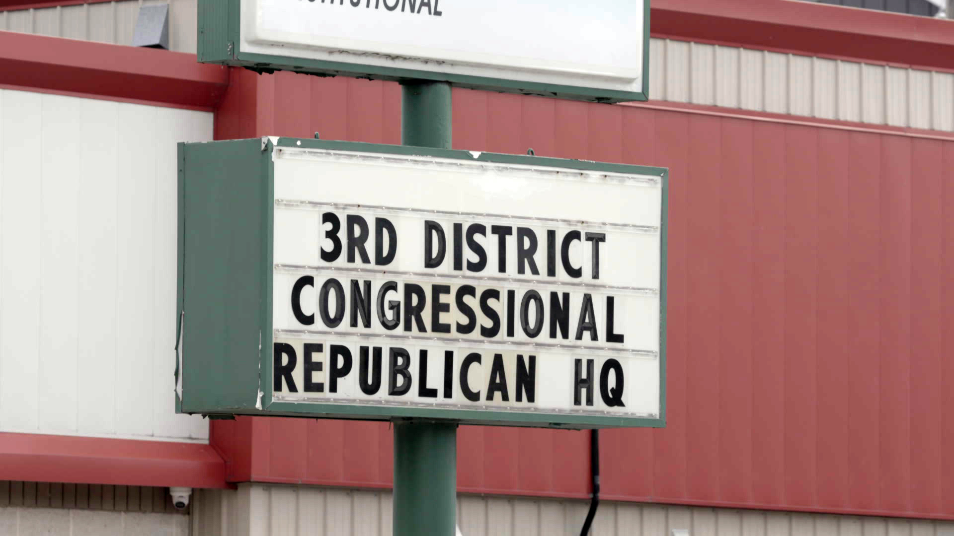 An outdoor changeable letter sign reads "3rd District Congressional Republican HQ" with a painted corrugated metal wall in the background.