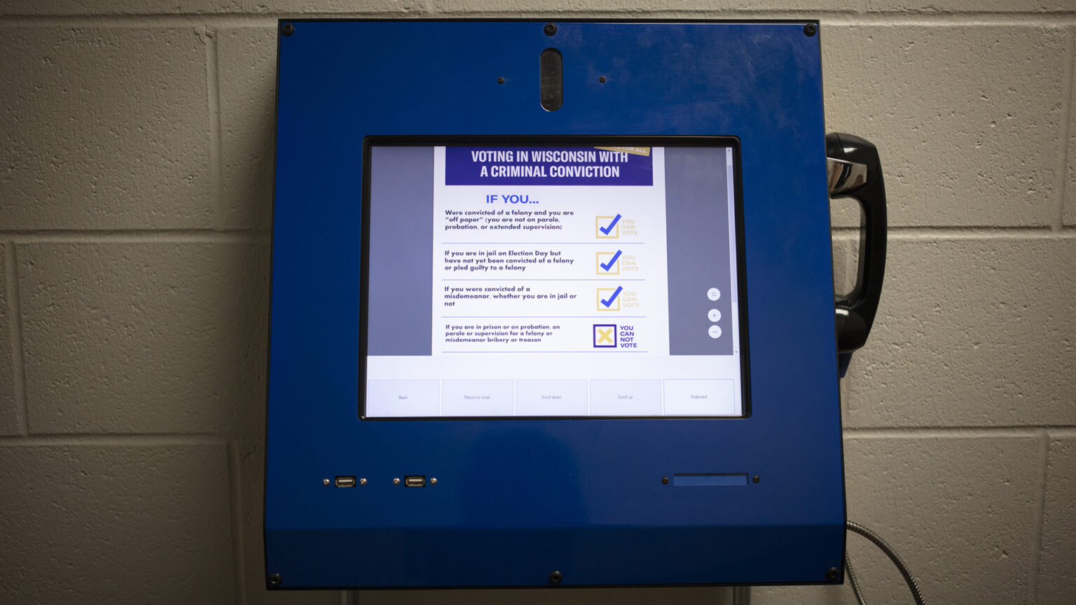 A metal box with a touchscreen and connected telephone handset shows information about Voting in Wisconsin with a Criminal Conviction.
