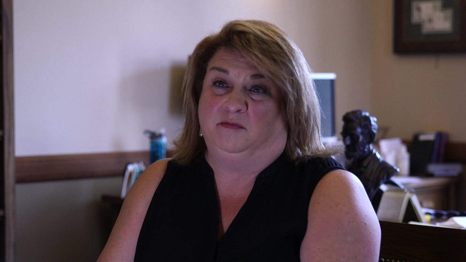 Janel Brandtjen sits in an office with a desk in the background.