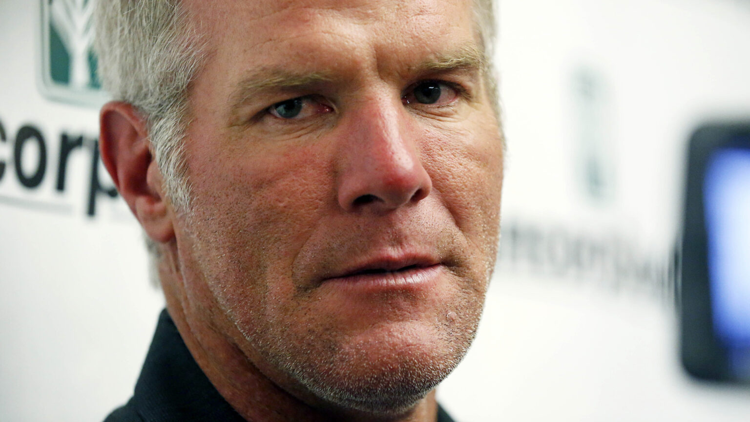 A close-up photos shows the face of Brett Favre with a logo backdrop in the background.