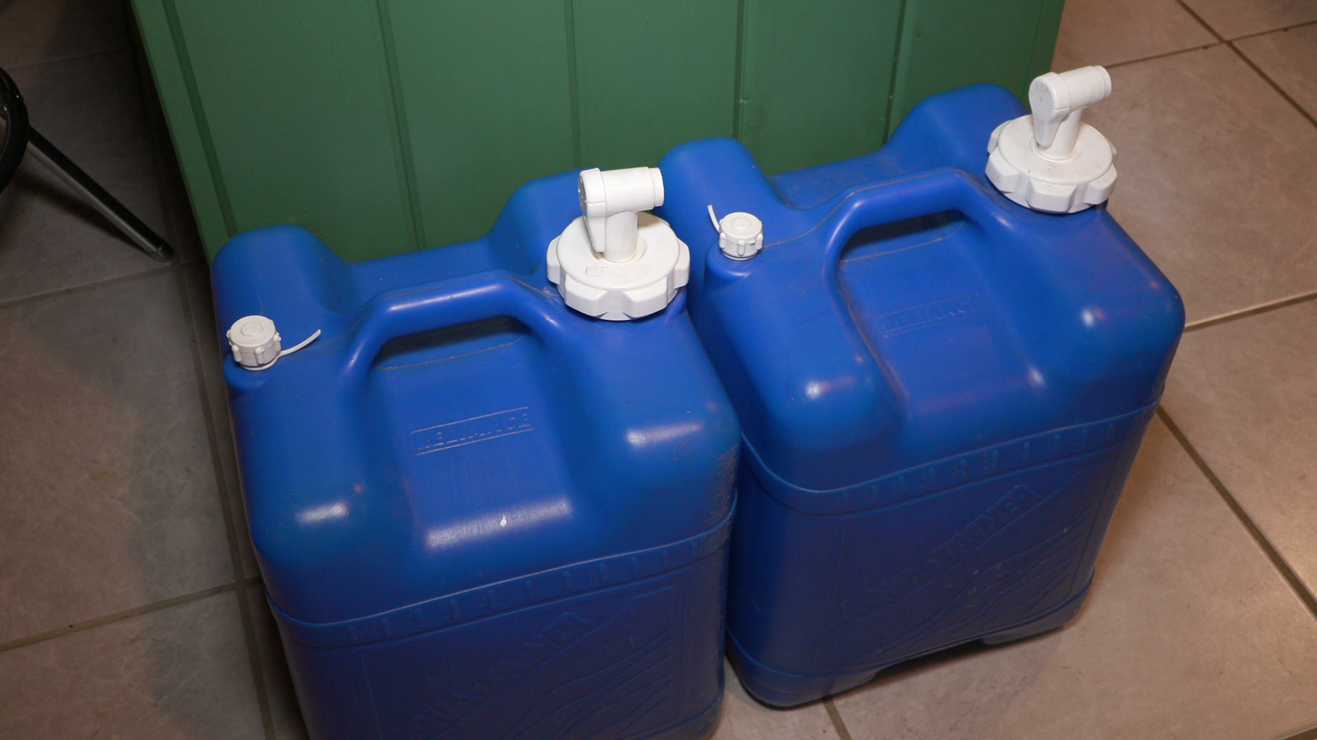 Two 7-gallon water jugs sit on a tile floor.