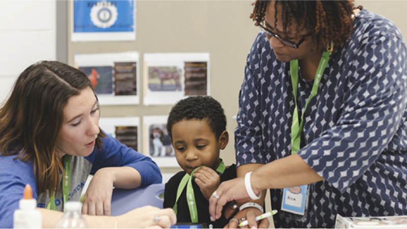 Two people work with a child at a classroom table