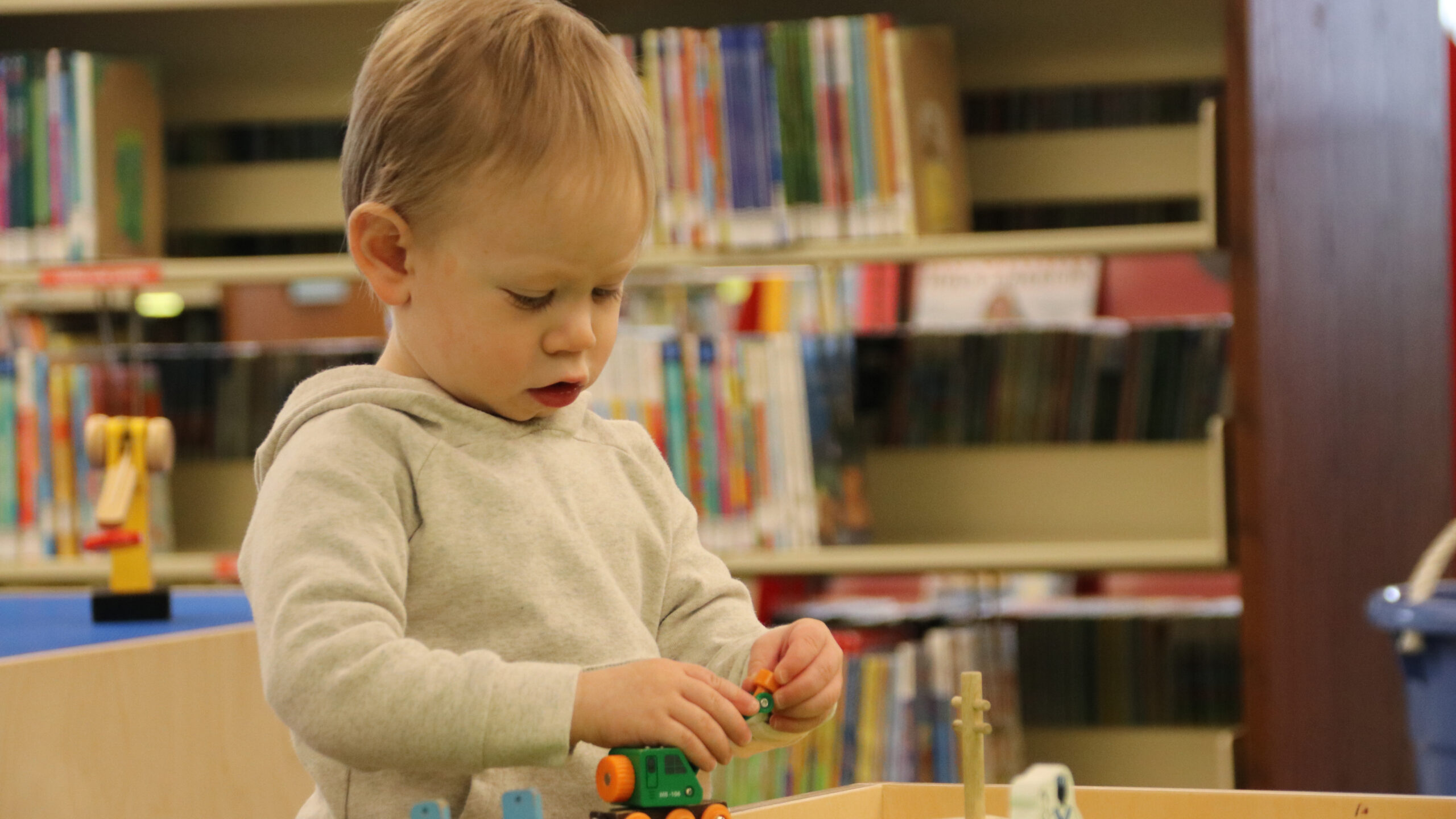 A child plays at a train table in a library.
