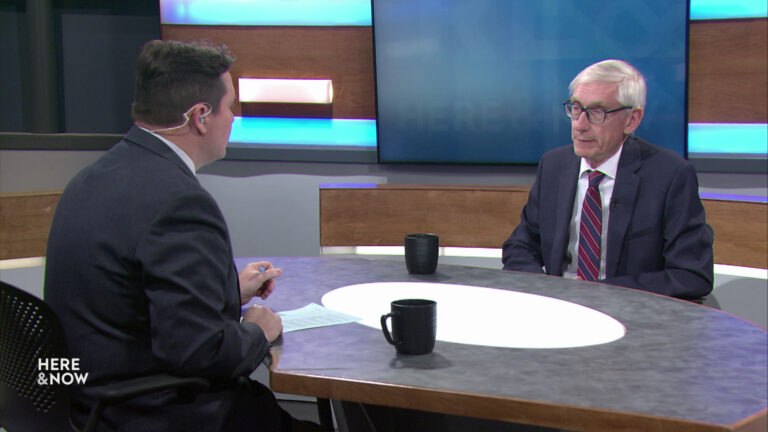 Zac Schultz and Tony Evers sit facing each other on the Here & Now set.