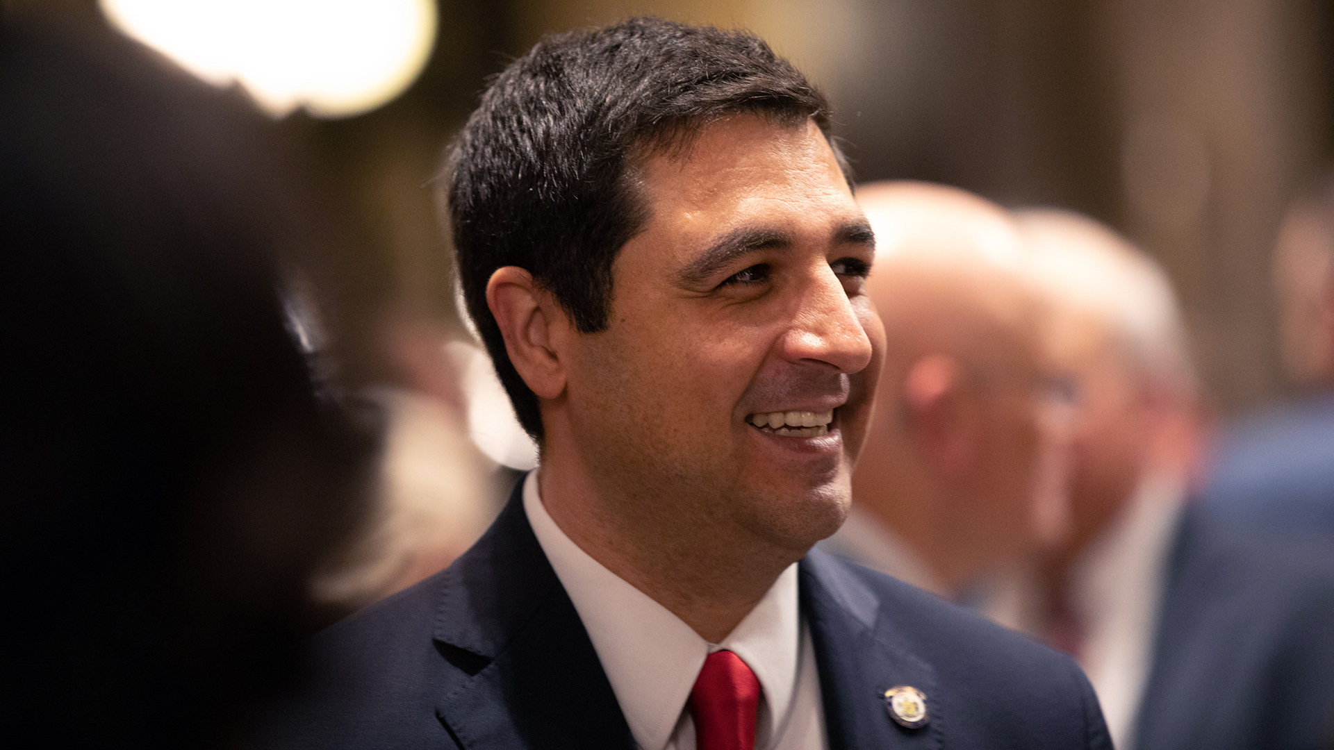 Josh Kaul smiles while standing in a group of people.