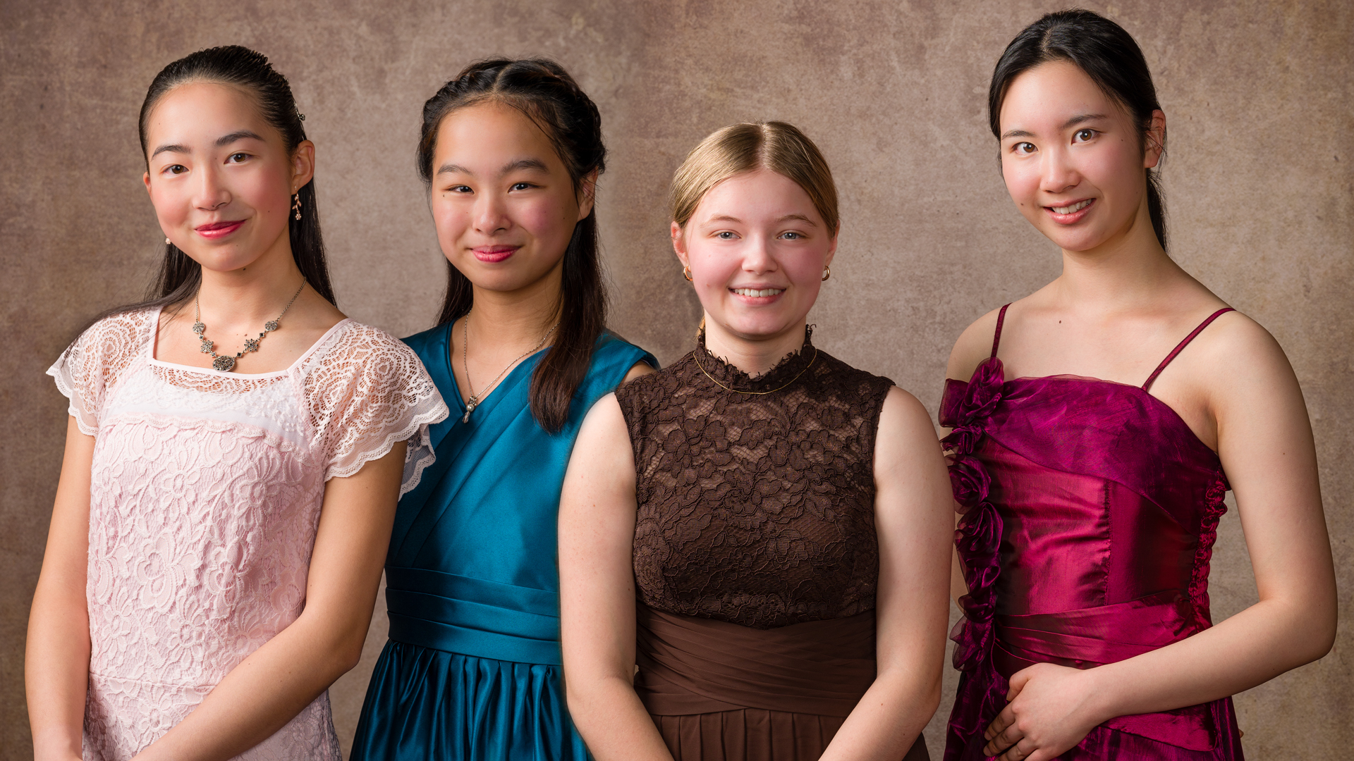 Four high school girls pose, smiling in formal wear