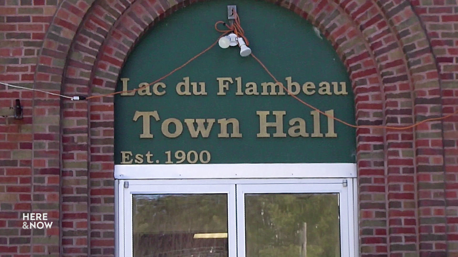 Signage reading "Lac du Flambeau Town Hall" is affixed above a door in a brick building.