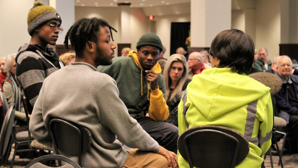 Four young men sit and talk together at a community screening.