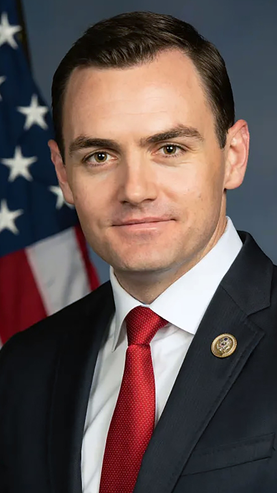 Mike Gallagher poses for a portrait with a U.S. flag in the background.