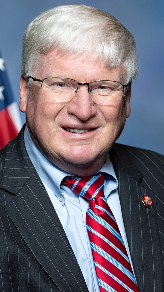 Glenn Grothman poses for a portrait with a U.S. flag in the background.