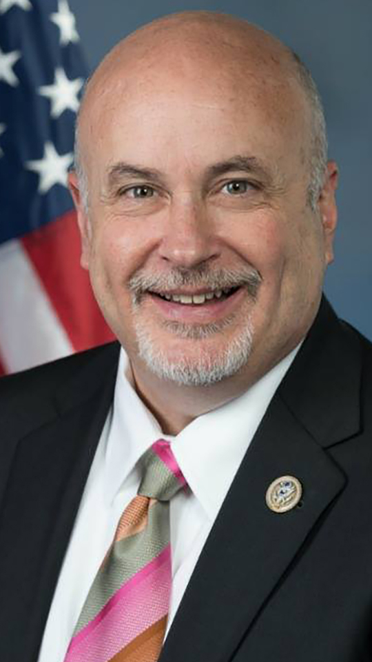 Mark Pocan poses for a portrait with a U.S. flag in the background.