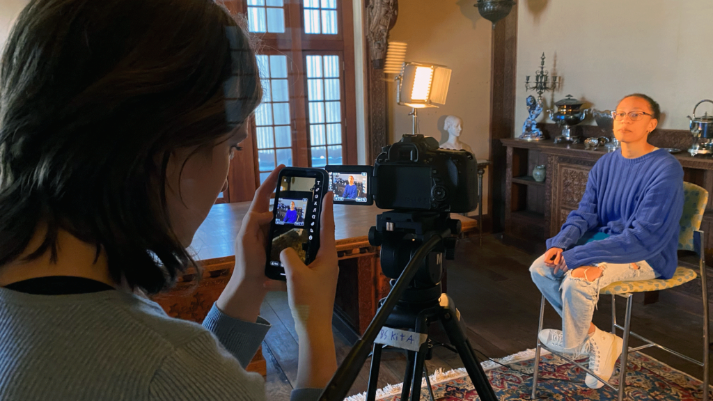 Two high school students use cameras and monitor equipment to conduct a documentary interview.