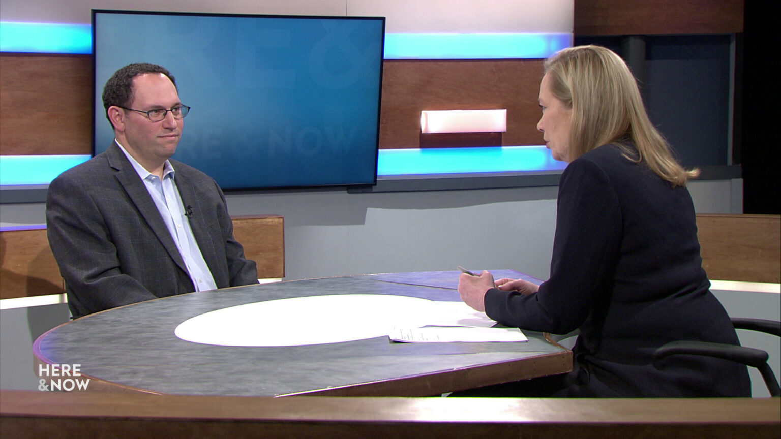 Jeff Mandell and Frederica Freyberg sit facing each other on the Here & Now set.