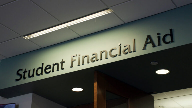 A lobby sign with letters on a wall above an open door reads Student Financial Aid.