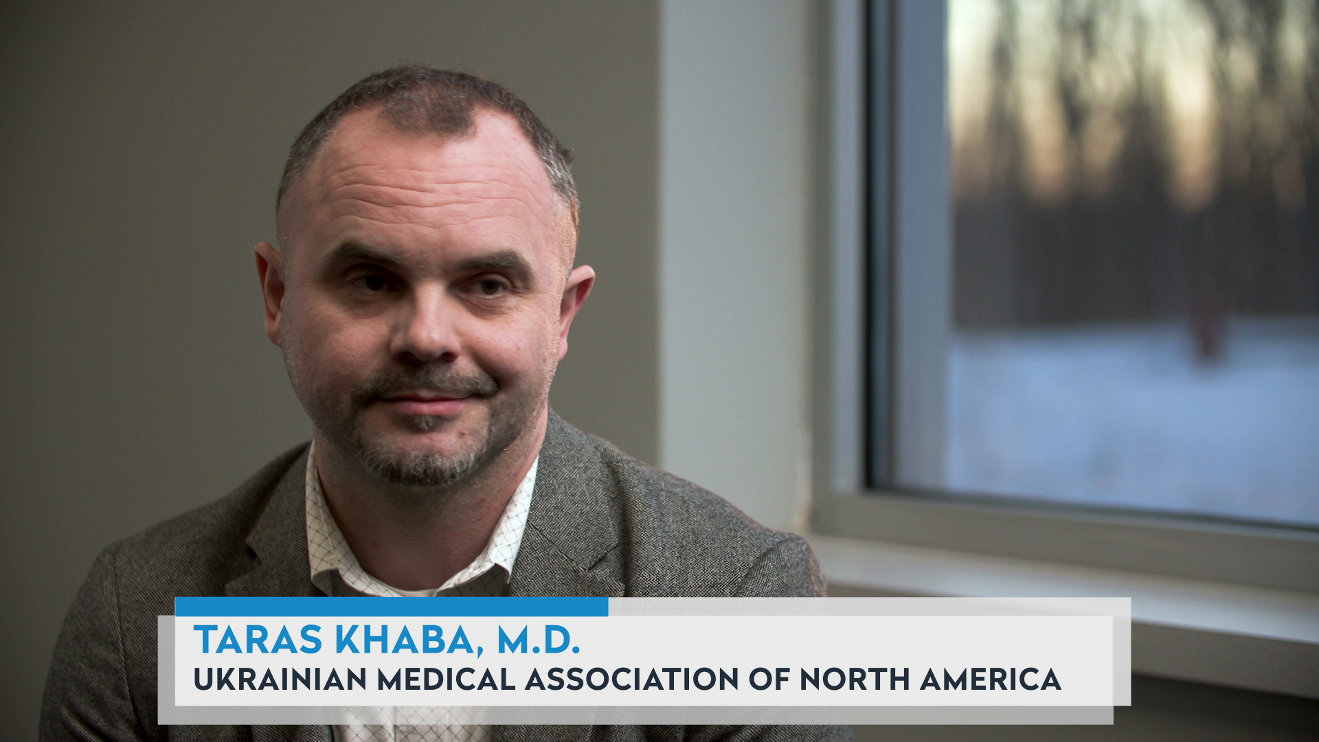 Taras Khaba sits in a room with a window behind his left shoulder, with a graphic at bottom reading "Taras Khaba, M.D." and "Ukrainian Medical Association of North America."