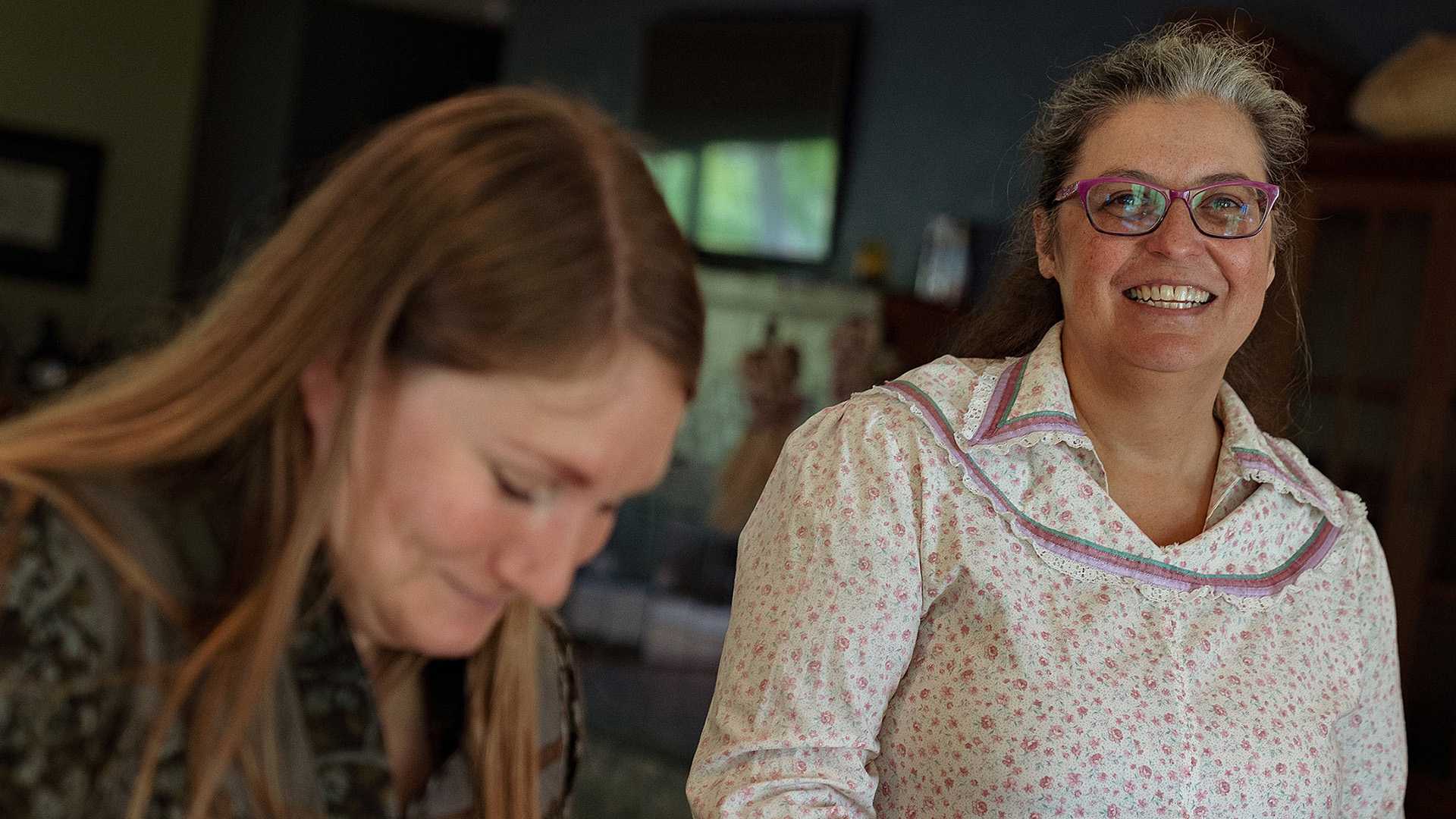Two women from the Oneida Nation of Wisconsin smile for the camera while in a kitchen making Oneida white corn soup.