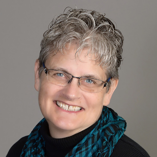 Portrait of a woman (JoAnne Lehman) wearing glasses and smiling.