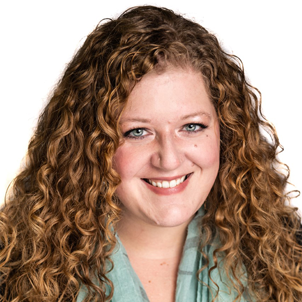 Portrait of a woman (Kristen Whitson) smiling in front of a white backdrop.