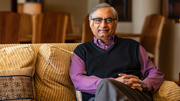 Portrait of Masood Akhtar sitting on a couch.