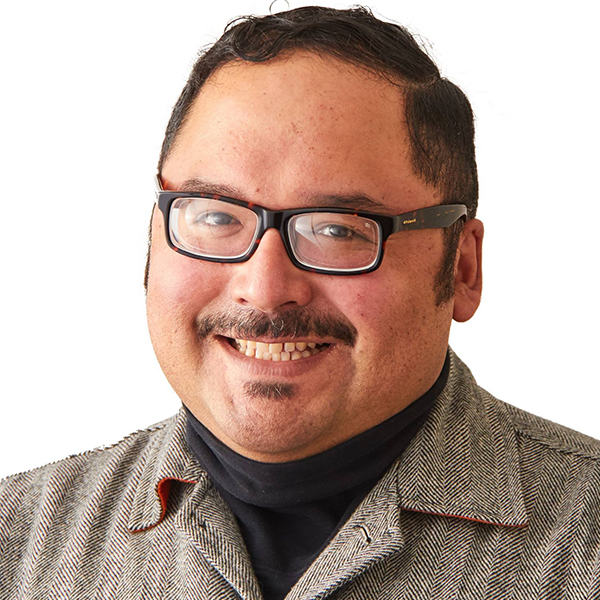 Portrait of a man (Víctor M. Macías-González) wearing glasses and smiling.