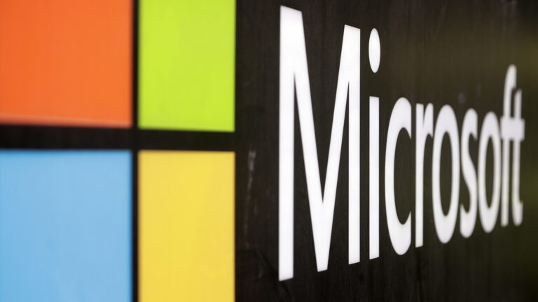 A close-up photo shows the Microsoft logo at an angle.