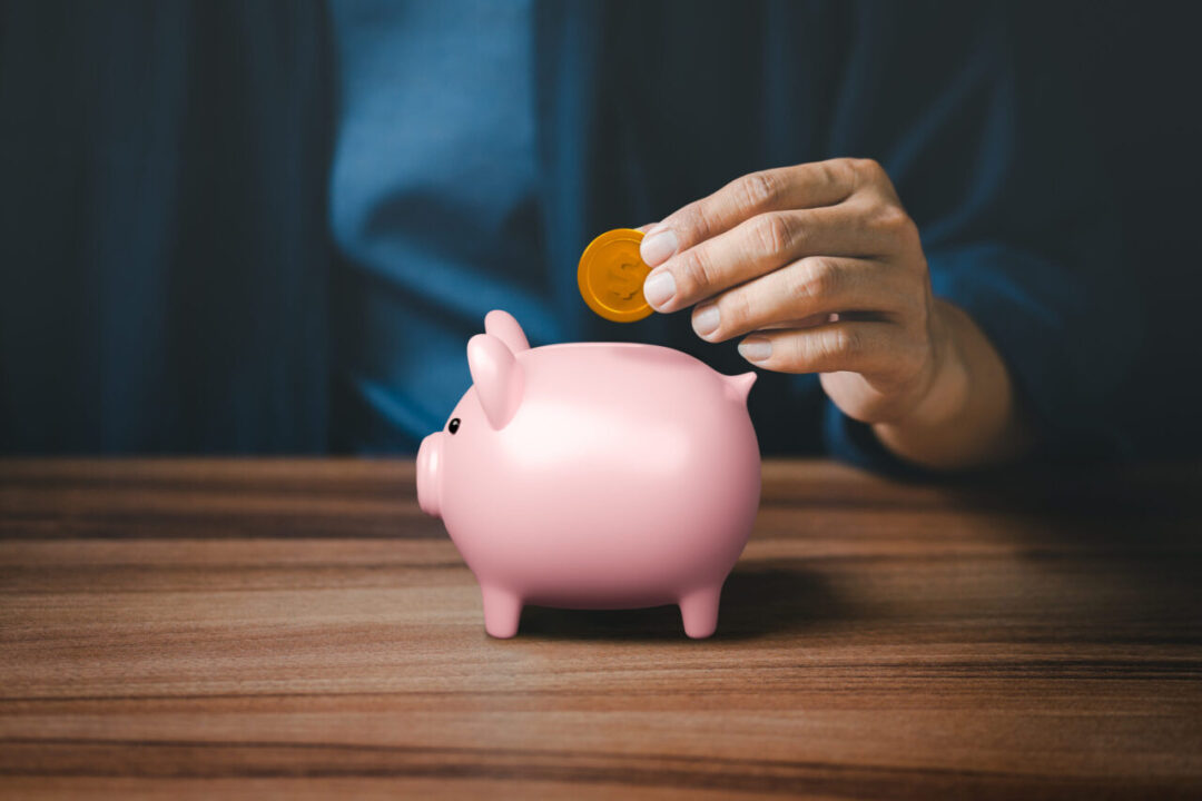 Man putting coin into pink piggy bank for saving money concept, business finance and investment.