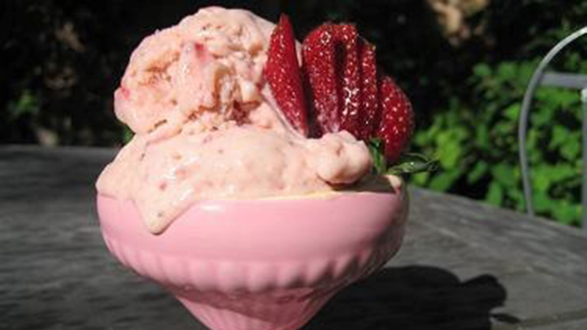 Strawberry ice cream in dish with sliced strawberries on top