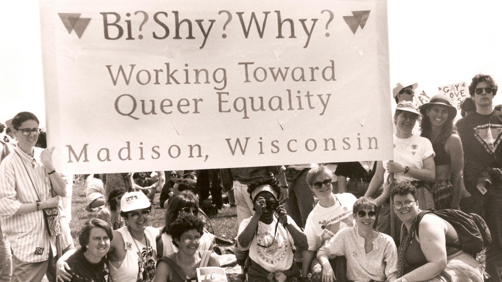 The Madison based bisexual support group active in the 1990s called Bi? Shy? Why? poses outdoors with its organizational banner.