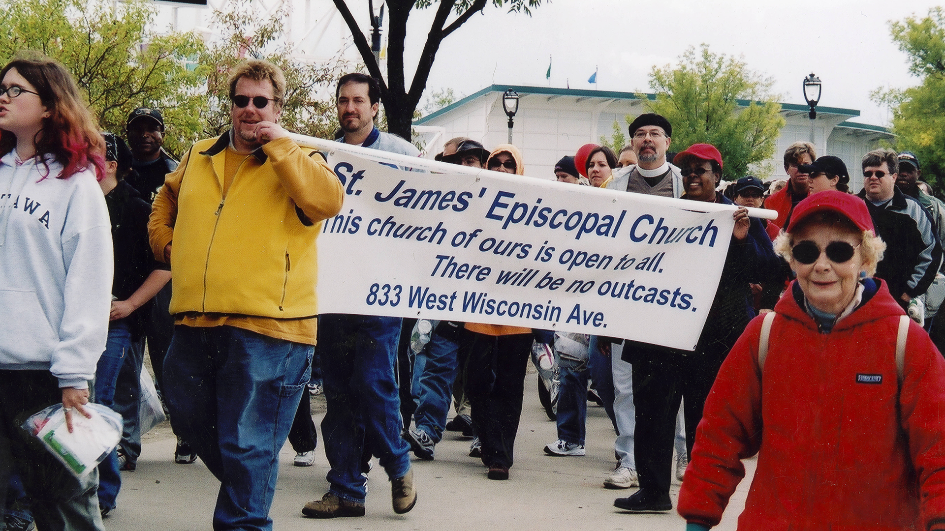 AIDS Walk Wisconsin: Walkers holding a sign that reads 'St. James Episcopal Church. This church of ours is open to all. There will be no outcasts.'