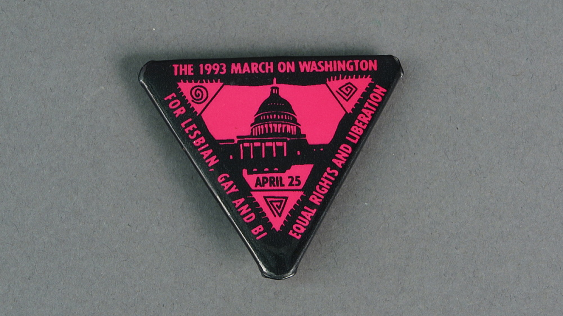 A black and pink pin in the shape of a triangle commemorates the on Washington for Lesbian, Gay, and Bi Equal Rights and Liberation which took place April 25, 1993.