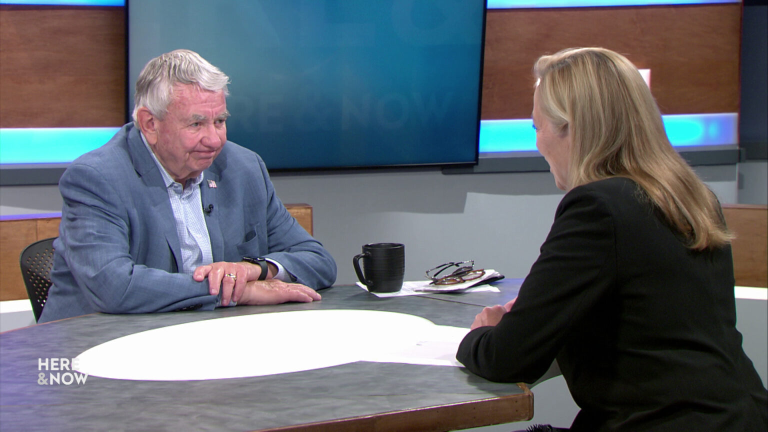 Tommy Thompson and Frederica Freyberg sit facing each other on the Here & Now set.