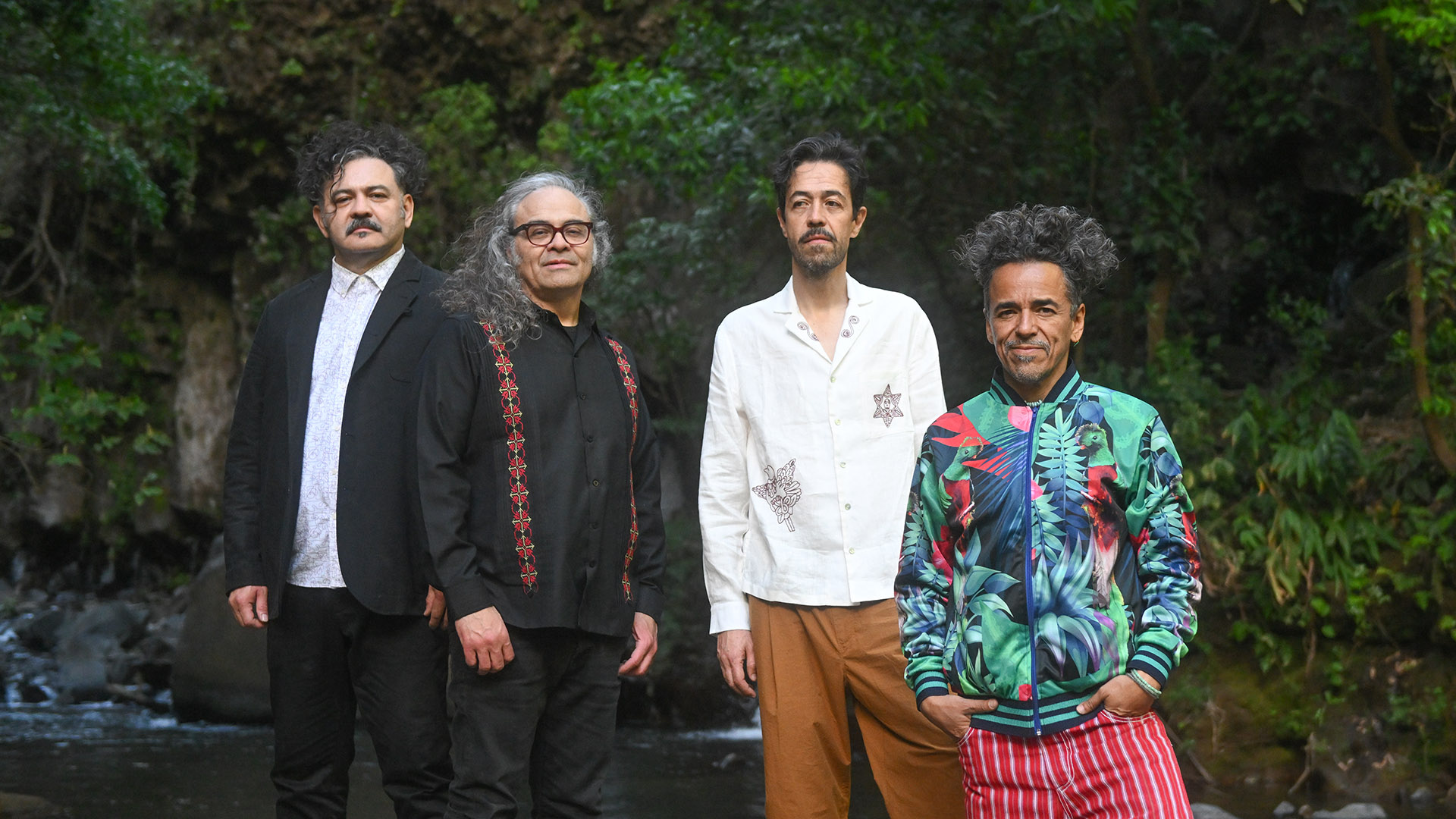 Four men stand in a row smiling at the camera.