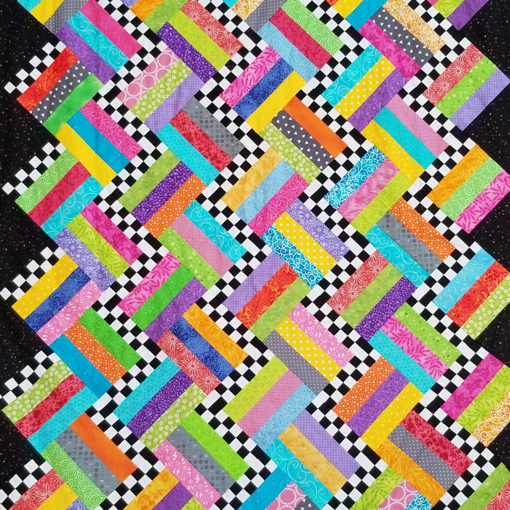 A quilt made in a wavy cascade of patches in bright colors and checkers
