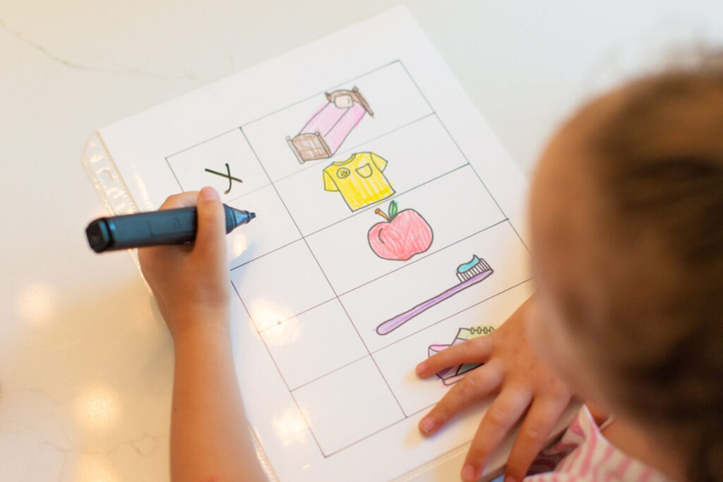 A child checks off items on a checklist of things to do during the morning, including making their bed, getting dressed, and eating breakfast.