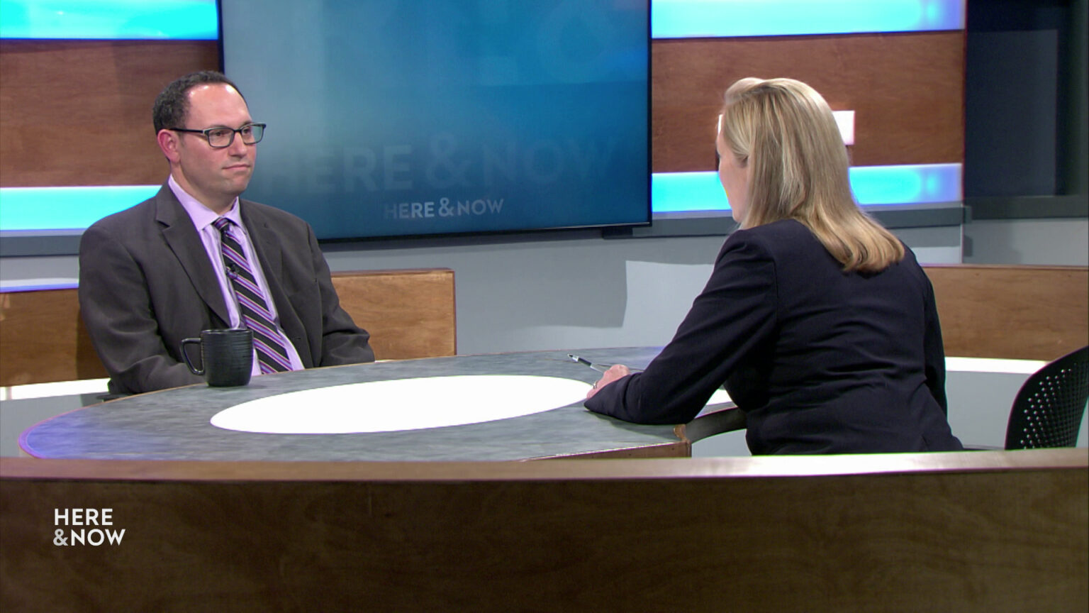 Jeff Mandell and Frederica Freyberg sit facing each other on the Here & Now set.