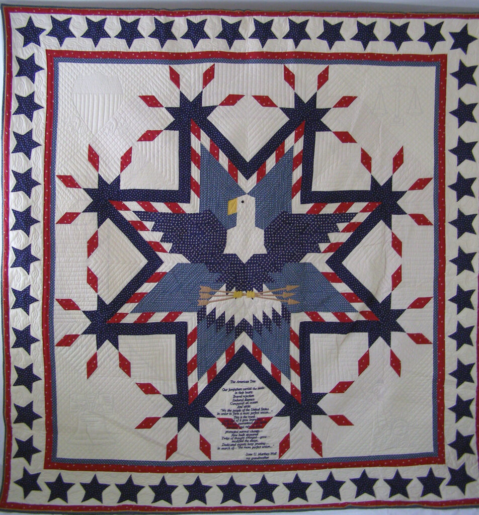 A red, white and blue quilt with an eagle in the middle of it.