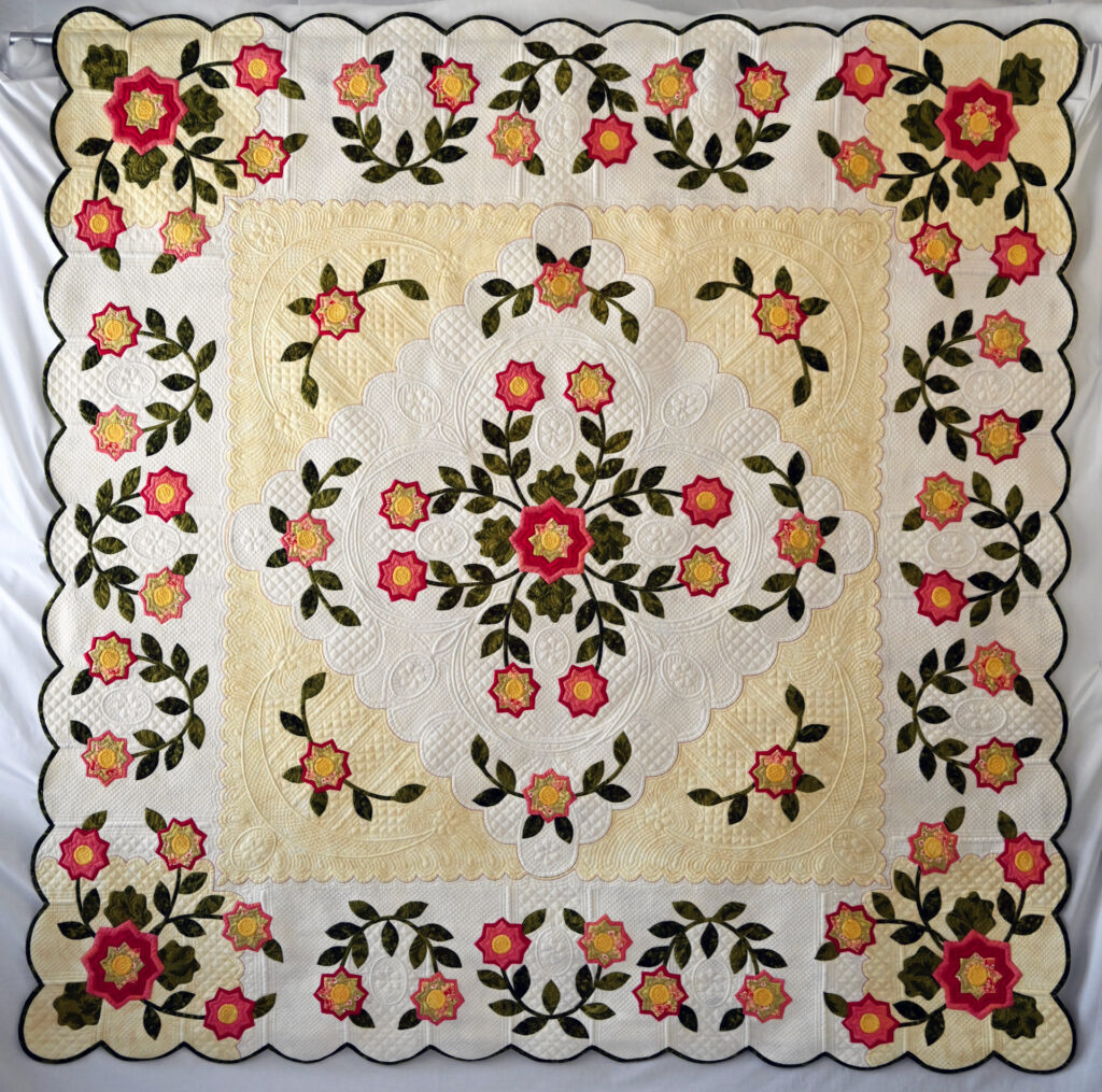 A floral, yellow, white and red medallion quilt.