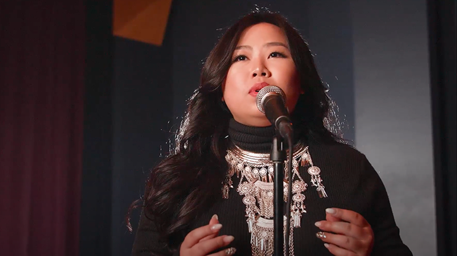 A woman sings into a microphone on a stage.