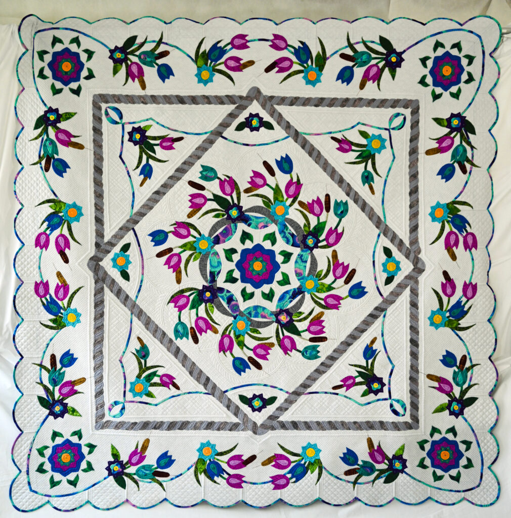 A floral medallion quilt with blues, purples and greens 