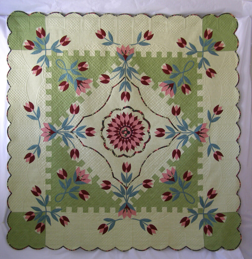 A green medallion quilt with pink and red tulips