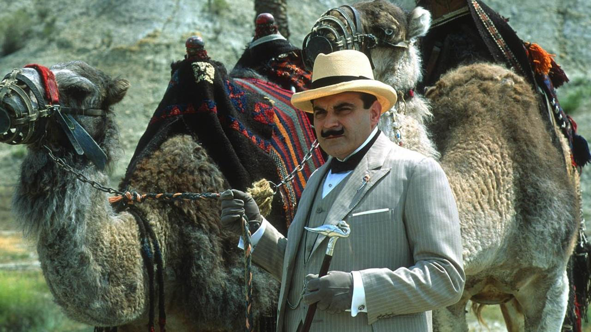An actor stands next to a camel.