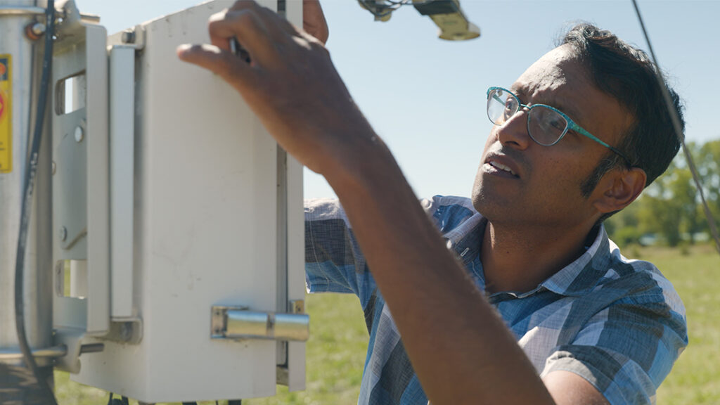 A man inspects science equipment on a sunny day