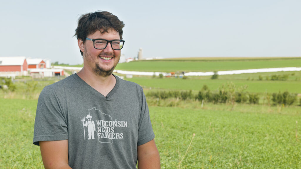 A smiling man is interviewed in a farm field