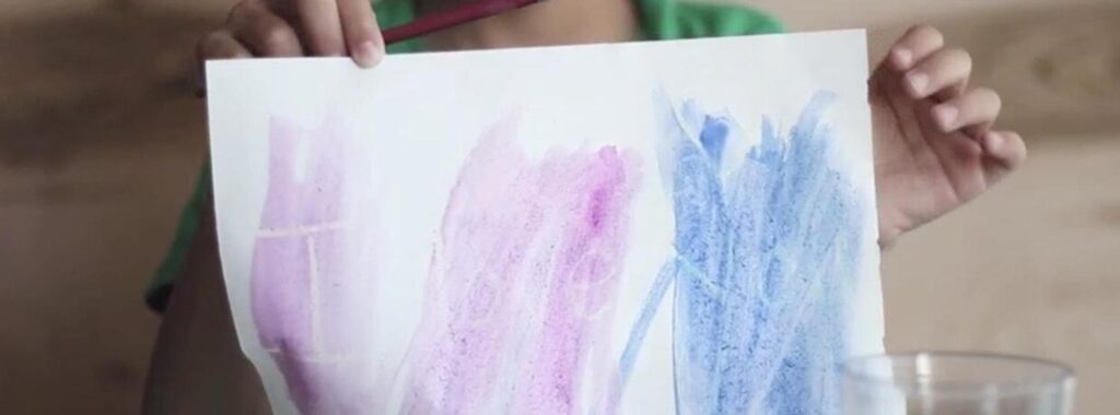 Close-up of a piece of paper with crayon and paint on it. 
