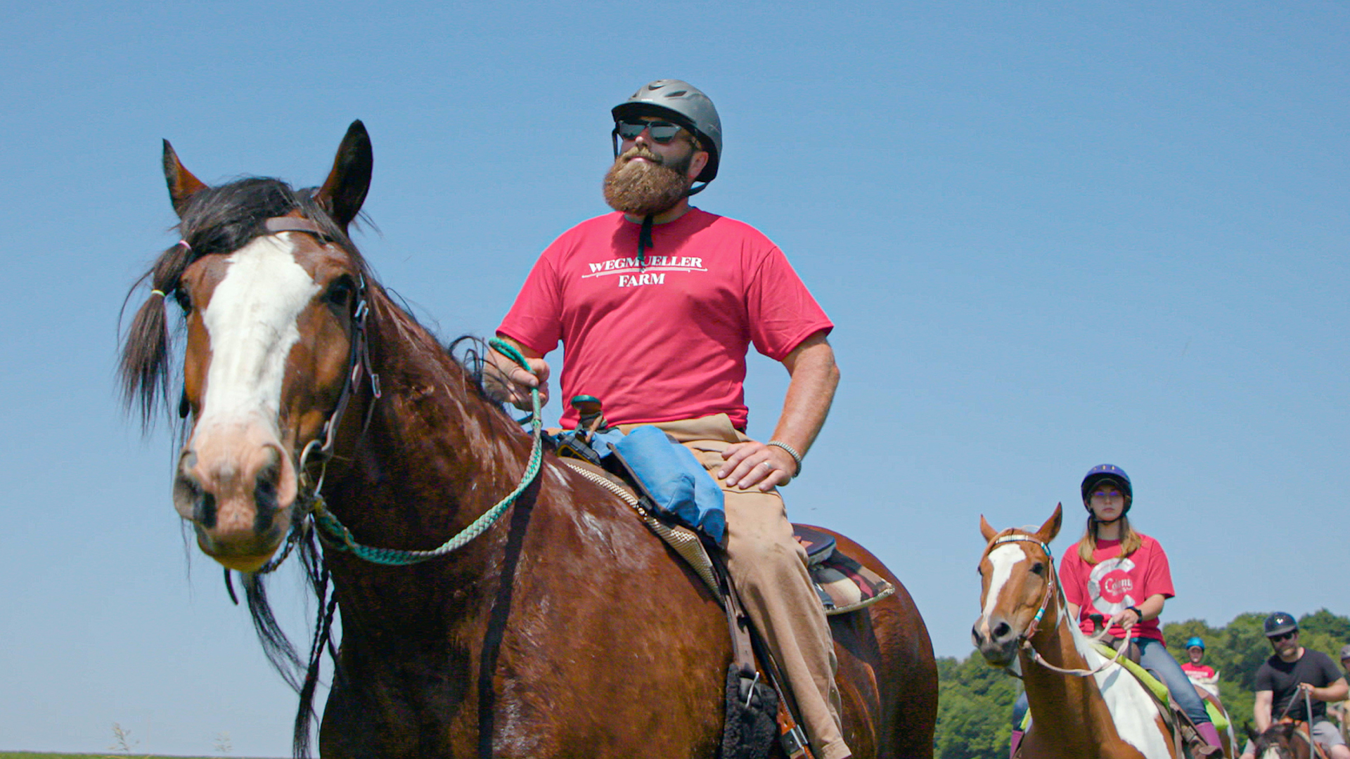 Farmer Dan Wegmueller guides a group of visitors on horseback.